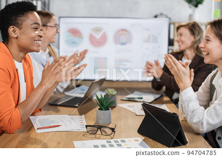 Close up of multiracial women clapping in hands while sitting together at office. 94704785