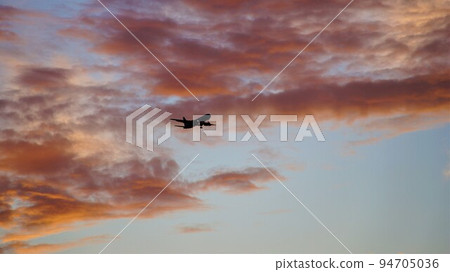 Burnt clouds and an airplane. 94705036