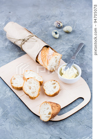 Cooking a hearty breakfast with fresh baguette, butter and quail eggs on a cutting board on a table. Vertical view Cooking a hearty breakfast with fresh baguette, butter and quail eggs on a cutting board on a table. Vertical view 94705078
