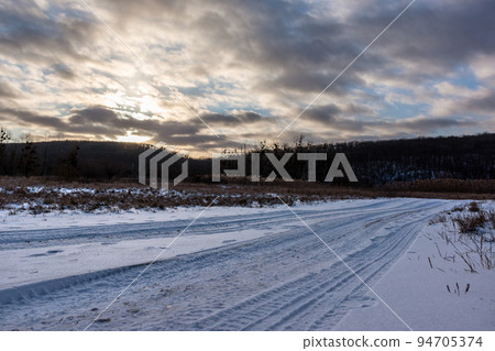Snowy white rural road in wintry countryside Snowy white rural road in wintry countryside 94705374