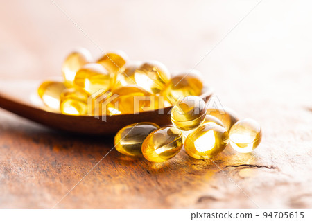 Fish oil capsules. Yellow omega 3 pills in spoon on wooden table. Fish oil capsules. Yellow omega 3 pills in spoon on wooden table. 94705615