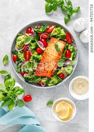 Grilled salmon fish fillet and fresh green leafy vegetable salad with tomatoes, red onion and broccoli. Healthy food. Ketogenic lunch. Top view 94705758