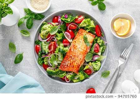Grilled salmon fish fillet and fresh green leafy vegetable salad with tomatoes, red onion and broccoli. Healthy food. Ketogenic lunch. Top view 94705760
