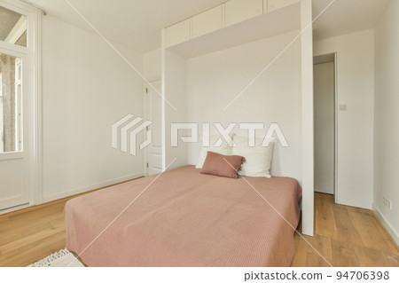 Comfortable bed located near balcony door with curtains in cozy light bedroom at home 94706398