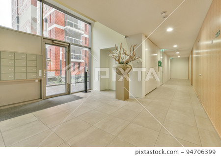 Corridor of contemporary apartment with black closets and opened doorway leading to terrace 94706399