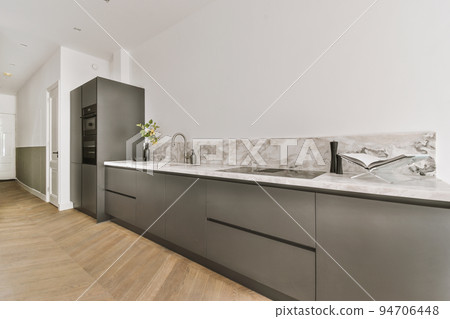Contemporary minimalist style interior design of light studio apartment with wooden table and chairs in dining zone between open kitchen and living room with white walls and parquet floor Contemporary minimalist style interior design of light studio apartment with wooden table and chairs in dining zone between open kitchen and living room with white walls and parquet floor 94706448