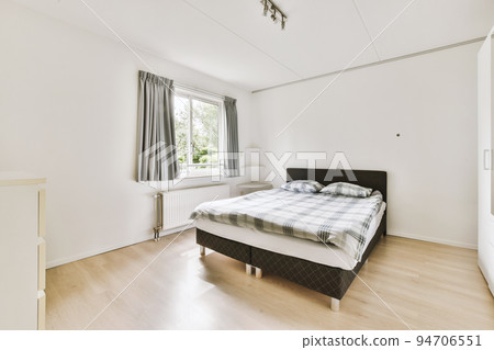 Home interior design of bedroom with bed and wooden wardrobe placed in corner near window in modern apartment Home interior design of bedroom with bed and wooden wardrobe placed in corner near window in modern apartment 94706551