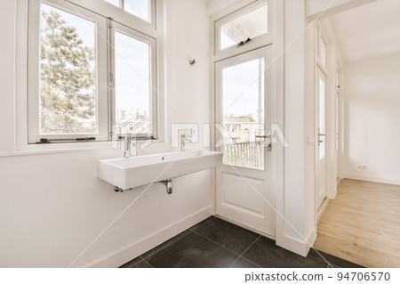 Sink with tap and liquid soap hanging on tiled wall under mirror in contemporary restroom at home 94706570