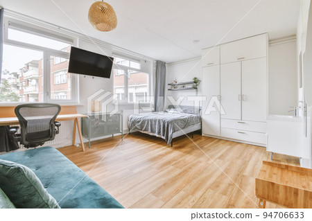 Home interior design of bedroom with bed and wooden wardrobe placed in corner near window in modern apartment Home interior design of bedroom with bed and wooden wardrobe placed in corner near window in modern apartment 94706633