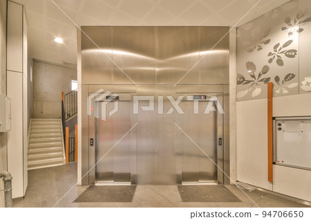 Light hallway with entrance door in two level apartment with minimalist wooden staircase leading upstairs in daylight Light hallway with entrance door in two level apartment with minimalist wooden staircase leading upstairs in daylight 94706650