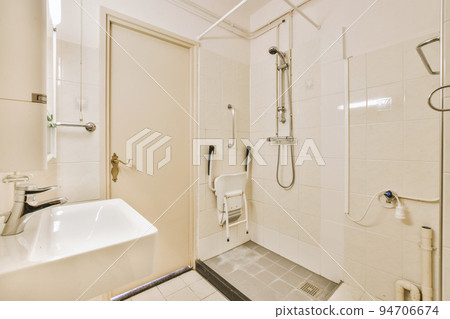 Sinks with mirrors and shower box with glass door in modern bathroom with white tiled walls Sinks with mirrors and shower box with glass door in modern bathroom with white tiled walls 94706674