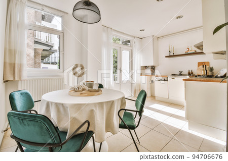 Interior of light kitchen and dining room with balcony doors in contemporary apartment at daytime Interior of light kitchen and dining room with balcony doors in contemporary apartment at daytime 94706676