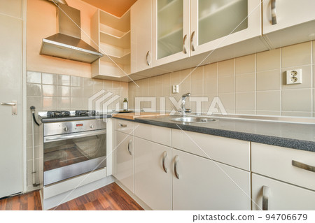 Interior of spacious light kitchen with modern white furniture and pop art portrait in light apartment Interior of spacious light kitchen with modern white furniture and pop art portrait in light apartment 94706679