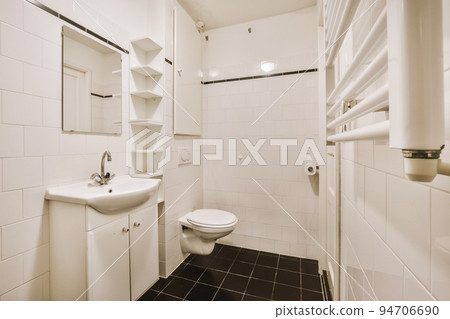 Sinks with mirrors and clean toilet located near shower box with glass door in modern bathroom with white tiled walls 94706690