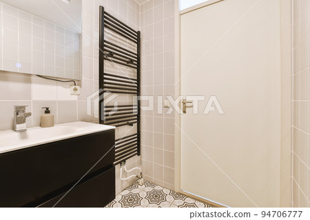 Sinks with mirrors and clean bathtub located near shower box with glass door in modern bathroom with white tiled walls 94706777