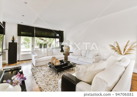 Stylish interior design of living room with light furniture and soft comfy couch and carpet and with TV and white walls. 94706881