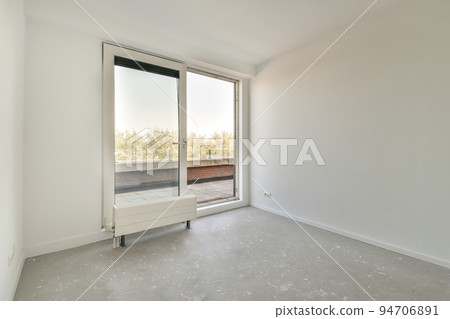 Interior of empty white room with large balcony windows with curtains and wooden parquet floor 94706891