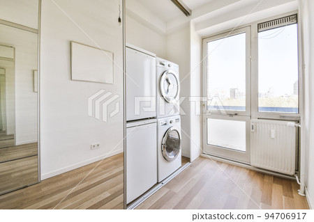 Interior of modern bright laundry room with white walls and dark reflect floor Interior of modern bright laundry room with white walls and dark reflect floor 94706917