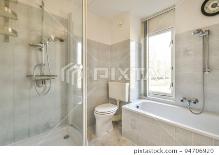 Modern home interior design of white bathroom with open bathtub and shower separated from toilet by partition wall 94706920