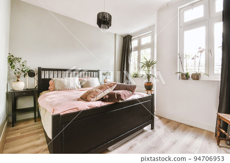 Home interior design of bedroom with bed and wooden wardrobe placed in corner near window in modern apartment Home interior design of bedroom with bed and wooden wardrobe placed in corner near window in modern apartment 94706953
