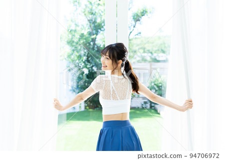 A young woman who opens the curtain and bathes in the sun 94706972