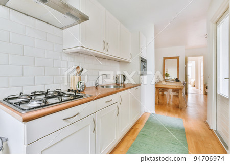 Well organized small home kitchen interior with sink under window and light furniture with stove and fridge in urban apartment Well organized small home kitchen interior with sink under window and light furniture with stove and fridge in urban apartment 94706974