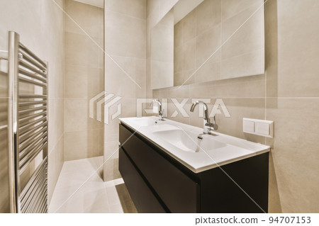 Sink with tap and liquid soap hanging on tiled wall under mirror in contemporary restroom at home 94707153