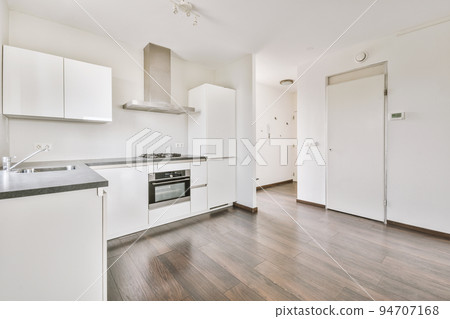 Interior of empty white kitchen with windows and wooden parquet floor 94707168