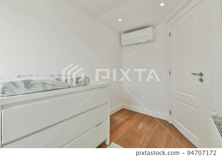 Interior of white room with baby crib and armchair near window with blue chest of drawers in daylight Interior of white room with baby crib and armchair near window with blue chest of drawers in daylight 94707172