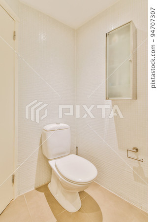 Interior of narrow restroom with sink and wall hung toilet with white walls and checkered floor 94707307