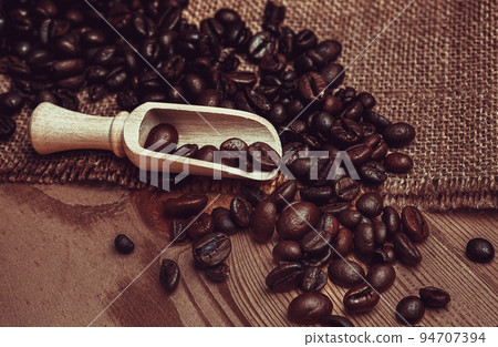Coffee cup with burlap sack of roasted beans on brown old wooden table. Coffee cup with burlap sack of roasted beans on brown old wooden table. 94707394