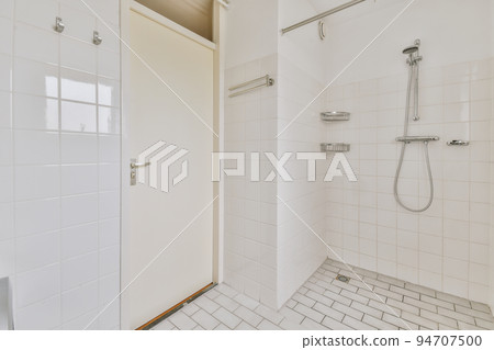 Sinks with mirrors and toilet near shower box with glass door in modern bathroom with white tiled walls Sinks with mirrors and toilet near shower box with glass door in modern bathroom with white tiled walls 94707500