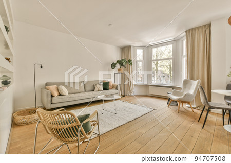 Table with chairs and flowers located near lounge area and kitchen in spacious room of contemporary apartment Table with chairs and flowers located near lounge area and kitchen in spacious room of contemporary apartment 94707508