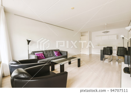 Shabby wooden table with chairs and vase located near comfortable couch against light walls with decorations and TV in modern apartment Shabby wooden table with chairs and vase located near comfortable couch against light walls with decorations and TV in modern apartment 94707511