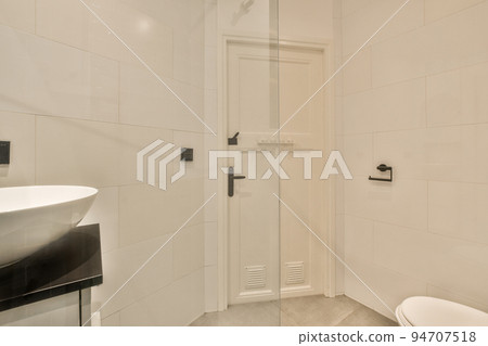 Flush toilet located between sink and shower in small tiled bathroom of contemporary apartment Flush toilet located between sink and shower in small tiled bathroom of contemporary apartment 94707518