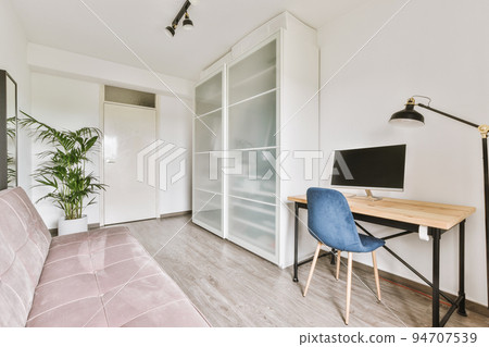 Comfortable chair placed near table with computer monitors against blank whiteboard and mirror in light home office in contemporary flat Comfortable chair placed near table with computer monitors against blank whiteboard and mirror in light home office in contemporary flat 94707539