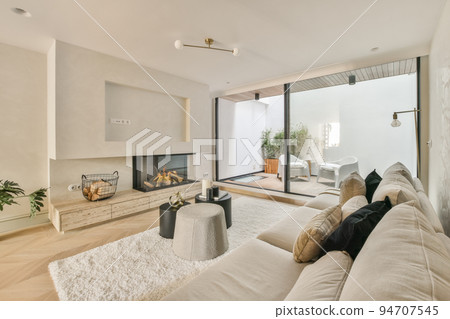 Large soft velvet couch with colorful cushions in living room with wooden parquet and kitchen island under ceiling with beams Large soft velvet couch with colorful cushions in living room with wooden parquet and kitchen island under ceiling with beams 94707545