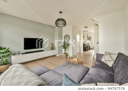 Comfortable sofas and wooden table placed near potted plants against window in living room of modern apartment with television 94707576