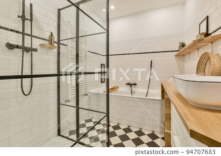 Interior of modern bathroom with rectangular mirror and clean sinks attached to white tiled wall near shower cabin in modern washroom Interior of modern bathroom with rectangular mirror and clean sinks attached to white tiled wall near shower cabin in modern washroom 94707683