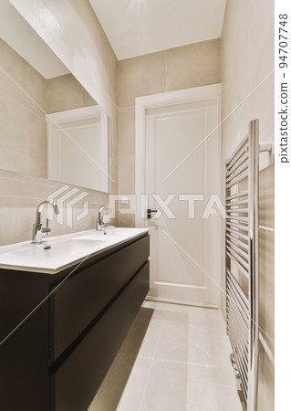 Sink with tap and liquid soap hanging on tiled wall under mirror in contemporary restroom at home 94707748