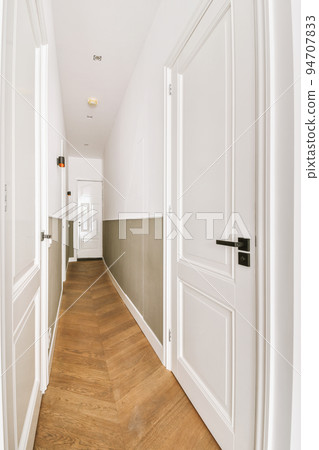 Light narrow hallway with many doors in white walls and glowing lamp over lumber floor Light narrow hallway with many doors in white walls and glowing lamp over lumber floor 94707833