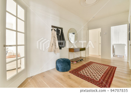 Narrow corridor with white walls and doors leading to spacious room with windows and parquet floor in modern apartment Narrow corridor with white walls and doors leading to spacious room with windows and parquet floor in modern apartment 94707835