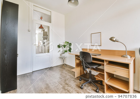 Comfortable chair placed near table with computer monitors against blank whiteboard and mirror in light home office in contemporary flat Comfortable chair placed near table with computer monitors against blank whiteboard and mirror in light home office in contemporary flat 94707836