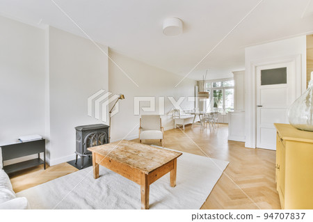Shabby wooden table with chairs and vase located near comfortable couch against light walls with decorations in modern apartment Shabby wooden table with chairs and vase located near comfortable couch against light walls with decorations in modern apartment 94707837