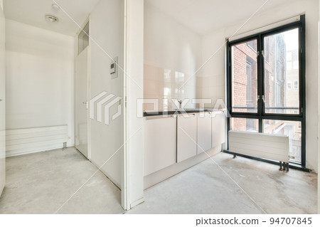 Interior of empty white kitchen with windows and wooden parquet floor 94707845