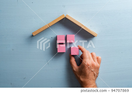 Male hand building a house of pink wooden blocks 94707869