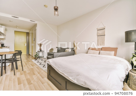 Table with chairs and flowers located near lounge area and kitchen in spacious room of contemporary apartment Table with chairs and flowers located near lounge area and kitchen in spacious room of contemporary apartment 94708076