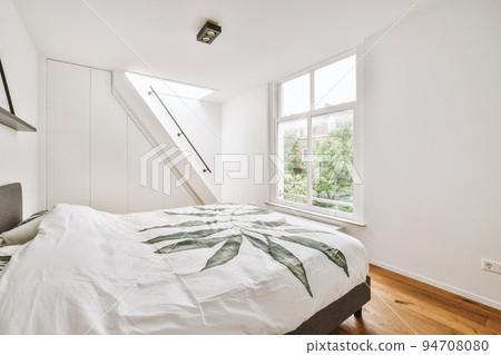 Home interior design of bedroom with bed and wooden wardrobe placed in corner near window in modern apartment 94708080