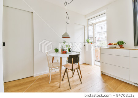 Home interior design of modern loft apartment with open kitchen in minimalist style and spacious dining zone with table and chairs 94708132