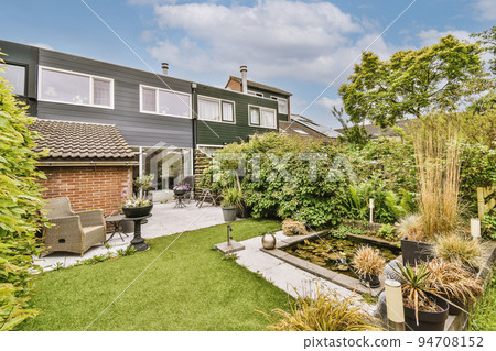 Neat paved patio with sitting area and small garden near wooden fence 94708152